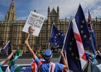 A pro-EU demonstrator holds a placard bearing an image of Russia's President Vladimir Putin, as others wave flags during a protest against Brexit, outside of the Houses of Parliament in central London on June 11, 2018. - After a rollercoaster week of Brexit rows within her government and with Brussels, British Prime Minister Theresa May will on Tuesday seek to avoid another setback in a long-awaited showdown with parliament. MPs in the House of Commons will vote on a string of amendments to a key piece of Brexit legislation that could force the government's hand in the negotiations with the European Union. (Photo by Daniel LEAL-OLIVAS / AFP)        (Photo credit should read DANIEL LEAL-OLIVAS/AFP/Getty Images)