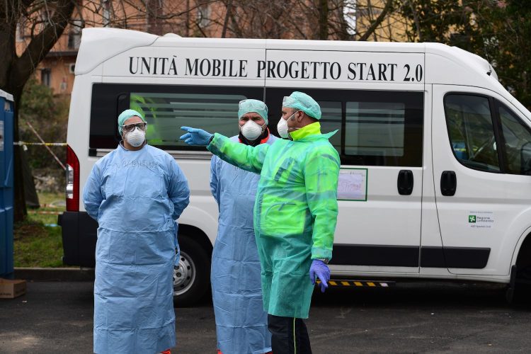 Hospital employees wearing a protection mask and gear work at a temporary emergency structure set up outside the accident and emergency department, where any new arrivals presenting suspect new coronavirus symptoms are being tested, at the Brescia hospital, Lombardy, on March 13, 2020. (Photo by Miguel MEDINA / AFP) (Photo by MIGUEL MEDINA/AFP via Getty Images)