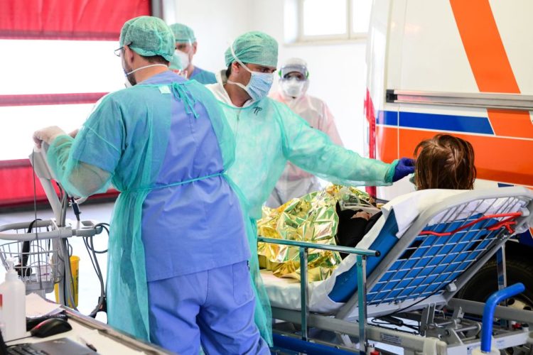 A medical worker wearing a face mask tends to a patient arriving on a stretcher at the new coronavirus intensive care unit of the Brescia Poliambulanza hospital, Lombardy, on March 17, 2020. (Photo by Piero CRUCIATTI / AFP) (Photo by PIERO CRUCIATTI/AFP via Getty Images)