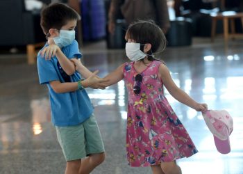 Two foreign children wearing facemasks play in front of the departure area of Ngurah Rai airport in Denpasar on February 8, 2020. - The new coronavirus that emerged in a Chinese market at the end of last year has killed more than 700 people and spread around the world. (Photo by SONNY TUMBELAKA / AFP) (Photo by SONNY TUMBELAKA/AFP via Getty Images)