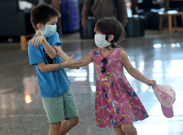 Two foreign children wearing facemasks play in front of the departure area of Ngurah Rai airport in Denpasar on February 8, 2020. - The new coronavirus that emerged in a Chinese market at the end of last year has killed more than 700 people and spread around the world. (Photo by SONNY TUMBELAKA / AFP) (Photo by SONNY TUMBELAKA/AFP via Getty Images)