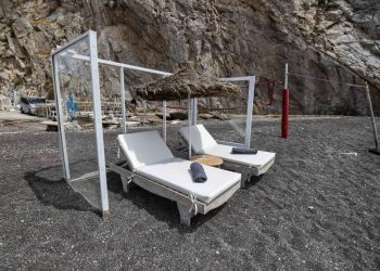 Plexiglass panels protect an umbrella and sunbeds as a preventive measure taken to curb the spread of the COVID-19 pandemic, caused by the novel coronavirus, on the beach of Perissa on the Greek Aegean island of Santorini on May 20, 2020. (Photo by Dimitris LAMBROPOULOS / AFP) (Photo by DIMITRIS LAMBROPOULOS/AFP via Getty Images)