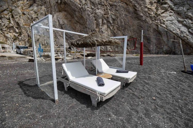 Plexiglass panels protect an umbrella and sunbeds as a preventive measure taken to curb the spread of the COVID-19 pandemic, caused by the novel coronavirus, on the beach of Perissa on the Greek Aegean island of Santorini on May 20, 2020. (Photo by Dimitris LAMBROPOULOS / AFP) (Photo by DIMITRIS LAMBROPOULOS/AFP via Getty Images)
