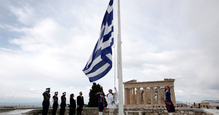 Members of the Presidential Guard raise the Greek flag in front of the Parthenon temple atop the Acropolis during celebrations of the 200th anniversary of the Greek War of Independence as Greek Prime Minister Kyriakos Mitsotakis and Greek President Katerina Sakellaropoulou attend the ceremony in Athens, Greece, March 25, 2021. Alexandros Vlachos/Pool via REUTERS