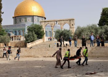 Palestinian medics walk near the Dome of the Rock as they evacuate on a stretcher a wounded protester from the Aqsa mosque compound in Jerusalem's Old City on May 10, 2021, amidst clashes with Israeli security forces. (Photo by ahmad gharabli / AFP) (Photo by AHMAD GHARABLI/AFP via Getty Images)