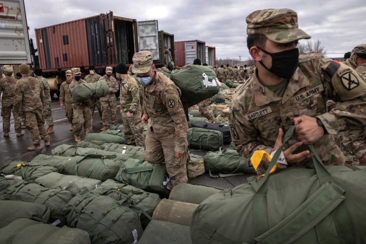 FORT DRUM, NEW YORK - DECEMBER 10: U.S. Army soldiers retrieve their duffel bags after they returned home from a 9-month deployment to Afghanistan on December 10, 2020 at Fort Drum, New York. The 10th Mountain Division soldiers who arrived this week are under orders to isolate with family at home or with fellow troops in barracks, finishing their quarantine just before Christmas. In the waning days of the Trump Administration and after 19 years of war, the U.S. military continues to reduce troop levels in Afghanistan.  (Photo by John Moore/Getty Images)