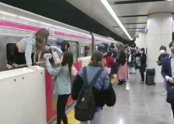 People escape through windows of a Tokyo train line following a knife, arson and acid attack, in Tokyo, Japan October 31, 2021 in this still image obtained from a social media video. TWITTER / @SIZ33/via REUTERS THIS IMAGE HAS BEEN SUPPLIED BY A THIRD PARTY. MANDATORY CREDIT. NO RESALES. NO ARCHIVES.