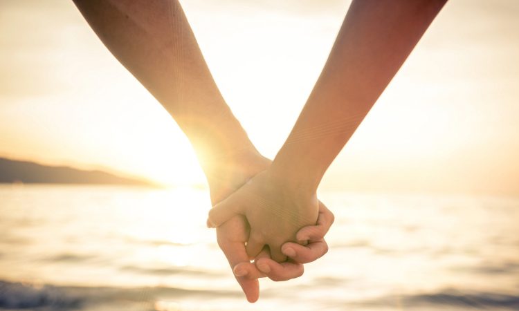 Couple of lovers holding their hands at a beautiful sunset over the ocean - Newlywed couple on a romantic vacation; Shutterstock ID 280073369
