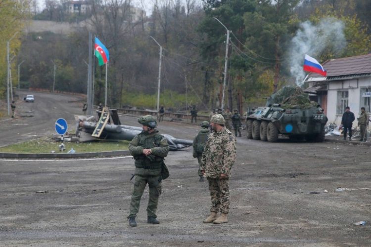 An Azerbaijani service member and a Russian peacekeeper stand guard at a checkpoint on the outskirts of Shusha (Shushi) in the region of Nagorno-Karabakh, November 13, 2020. REUTERS/Stringer