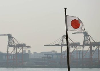 epa04082768 Japan's national flag is seen with container cranes in the background in Tokyo, Japan, 17 February 2014. The Japanese government said the economy grew at an annual rate of one percent in the October-December period, less than expected amid weak export growth.  EPA/FRANCK ROBICHON
