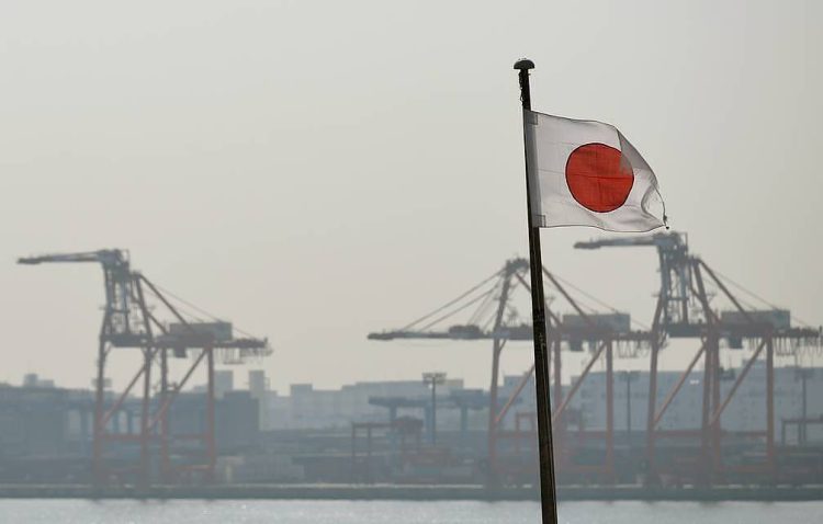 epa04082768 Japan's national flag is seen with container cranes in the background in Tokyo, Japan, 17 February 2014. The Japanese government said the economy grew at an annual rate of one percent in the October-December period, less than expected amid weak export growth.  EPA/FRANCK ROBICHON
