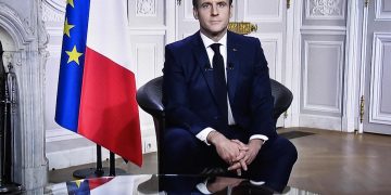 This photograph shows a television screen broadcasting French President Emmanuel Macron delivering his New Year wishes during an address to the nation from the Elysee Palace, in Paris, on December 31, 2020. (Photo by STEPHANE DE SAKUTIN / AFP)