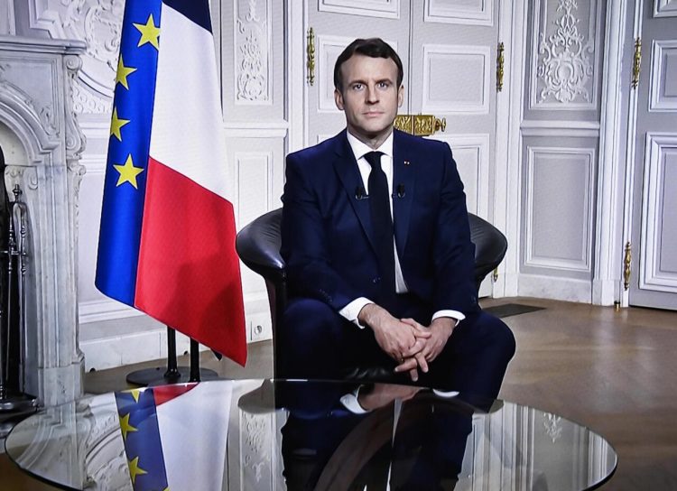 This photograph shows a television screen broadcasting French President Emmanuel Macron delivering his New Year wishes during an address to the nation from the Elysee Palace, in Paris, on December 31, 2020. (Photo by STEPHANE DE SAKUTIN / AFP)