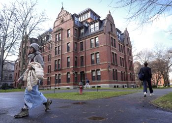 FILE - People walk between buildings, Dec. 17, 2024, on the campus of Harvard University in Cambridge, Mass. (AP Photo/Steven Senne, File)
