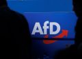FILED - 28 July 2023, Saxony-Anhalt, Magdeburg: People walk in front of the party logo at the Alternative for Germany (AfD) party conference in Magdeburg. Photo: Carsten Koall/dpa