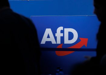 FILED - 28 July 2023, Saxony-Anhalt, Magdeburg: People walk in front of the party logo at the Alternative for Germany (AfD) party conference in Magdeburg. Photo: Carsten Koall/dpa