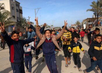 TOPSHOT - Children cheer in Nuseirat in the central Gaza Strip on January 19, 2025, shortly before a ceasefire deal in the war between Israel and the Palestinian militant group Hamas was implemented. (Photo by Bashar TALEB / AFP) (Photo by BASHAR TALEB/AFP via Getty Images)