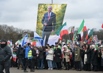 Teilnehmende einer Demonstration «Menschenrechte und Freiheit im Iran. Internationale Solidarität mit dem iranischen Volk» anlässlich der Münchner Sicherheitskonferenz stehen auf der Theresienwiese. Sie halten ein Überlebensgroßes Plakat von Reza Pahlavi hoch. Foto: Malin Wunderlich/dpa