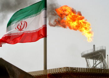 FILE PHOTO: A gas flare on an oil production platform is seen alongside an Iranian flag in the Gulf July 25, 2005. REUTERS/Raheb Homavandi/File Photo