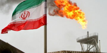 FILE PHOTO: A gas flare on an oil production platform is seen alongside an Iranian flag in the Gulf July 25, 2005. REUTERS/Raheb Homavandi/File Photo