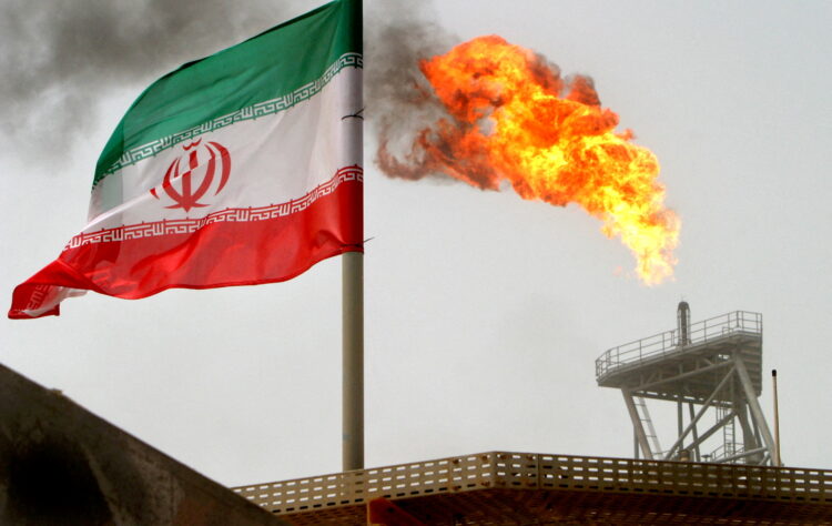 FILE PHOTO: A gas flare on an oil production platform is seen alongside an Iranian flag in the Gulf July 25, 2005. REUTERS/Raheb Homavandi/File Photo